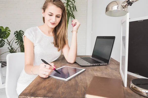 Joven mujer de negocios que trabaja en casa y se basa en la tableta. Espacio de trabajo de estilo escandinavo creativo — Foto de Stock