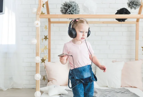 Linda niña escuchando música en los auriculares en casa . — Foto de Stock