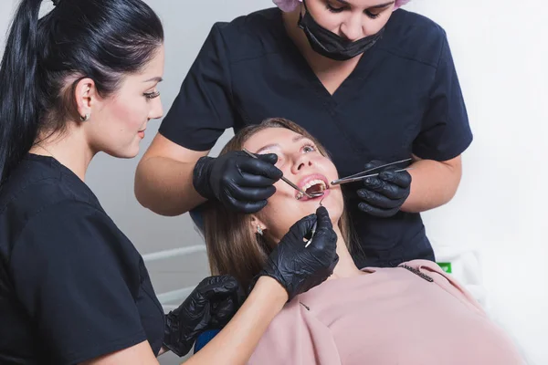 Clínica dental. Recepción, examen del paciente. Cuidado de los dientes. Mujer joven se somete a un examen dental por un dentista — Foto de Stock