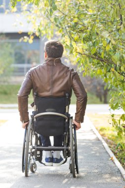 Genç biri tekerlekli sandalyede park yol boyunca rides.