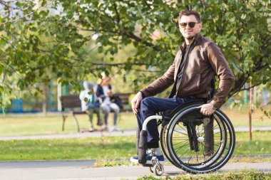 Genç biri tekerlekli sandalyede park yol boyunca rides.
