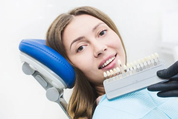 Clínica dentária. Recepção, exame do paciente. Cuidado com os dentes. Dentista com amostras de cor de dente escolhendo sombra para mulheres dentes de paciente na clínica odontológica — Fotografia de Stock