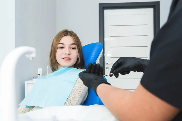 Clínica dental. Recepción, examen del paciente. Cuidado de los dientes. Dentista femenina en consultorio dental hablando con paciente chica . — Foto de Stock