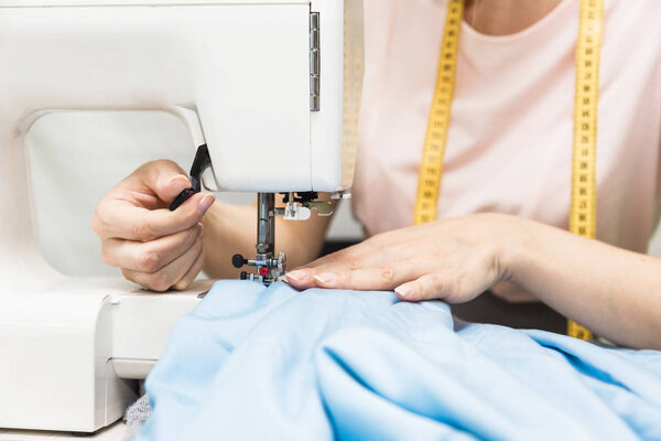 Швейная мастерская. Швея на работе. Молодая женщина работает с швейной машинкой
.