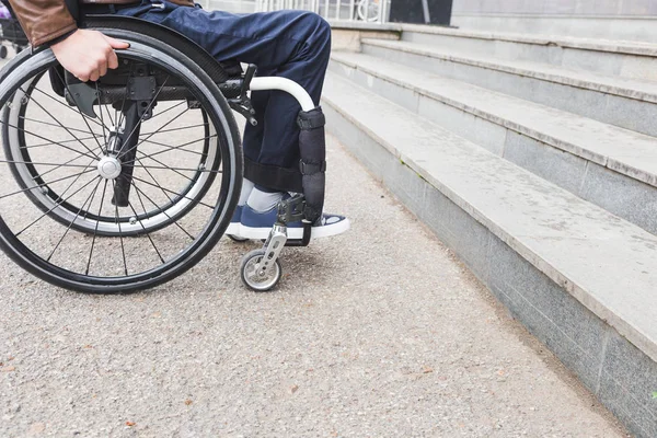 Man in wheelchair in front of stairs.