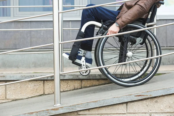 El hombre en silla de ruedas usa una rampa para silla de ruedas . — Foto de Stock