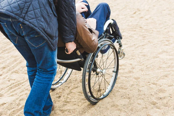 Jonge man in rolstoel met zijn assistent op een wandeling door het park. — Stockfoto