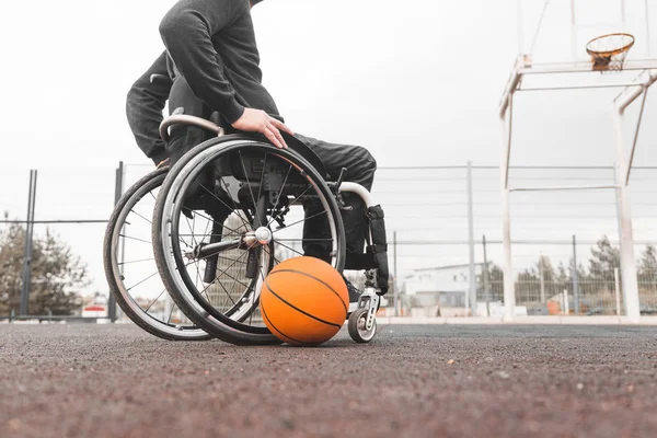 Jovem em uma cadeira de rodas jogando basquete . — Fotografia de Stock