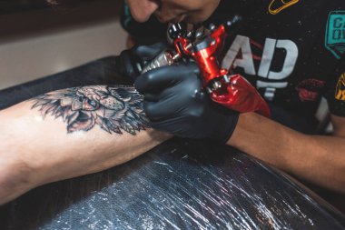 Dövme sanatçısı bir adamın vücudunda bir resim oluşturur. dövme makineleri ve elleri yakın çekim