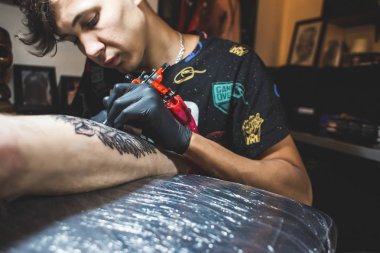 Dövme sanatçısı bir adamın vücudunda bir resim oluşturur. dövme makineleri ve elleri yakın çekim