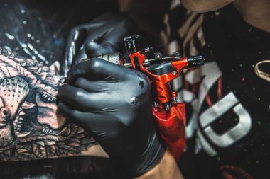 Dövme sanatçısı bir adamın vücudunda bir resim oluşturur. dövme makineleri ve elleri yakın çekim