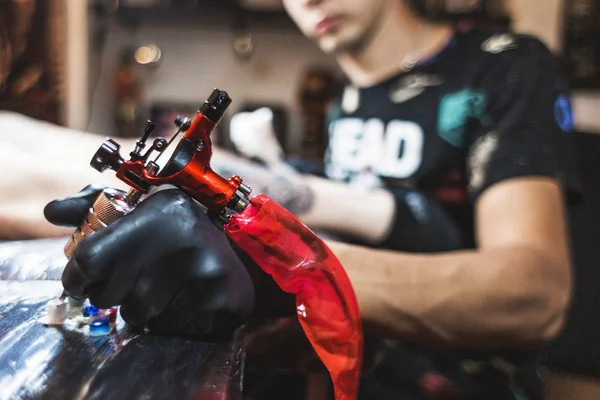タトゥー アーティストは、男の体の画像を作成します。タトゥー マシンと塗料のクローズ アップ — ストック写真