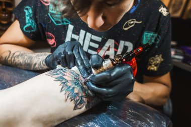 Dövme sanatçısı bir adamın vücudunda bir resim oluşturur. dövme makineleri ve elleri yakın çekim