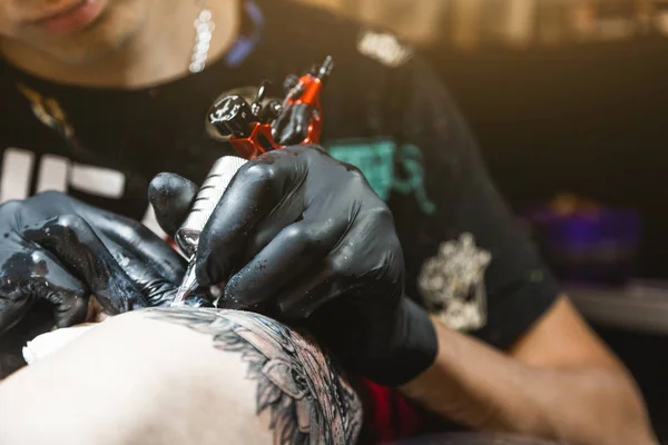 De tatoeage kunstenaar creëert een beeld op het lichaam van een man. Close-up van tattoo machines en verven — Stockfoto