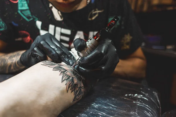 Tattoo umělec vytvoří obrázek na těle muže. Detail tetovací strojky a ruce — Stock fotografie