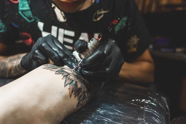 O tatuador cria uma imagem no corpo de um homem. close-up de máquinas de tatuagem e mãos — Fotografia de Stock