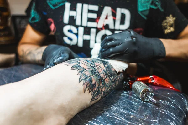 Tatuażysta tworzy obraz na organizm człowieka. zbliżenie do tatuażu i ręce — Zdjęcie stockowe