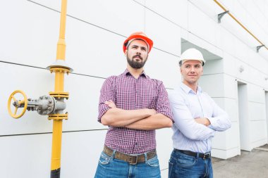 Bina arka plan üzerinde kask içinde iki erkek mühendis