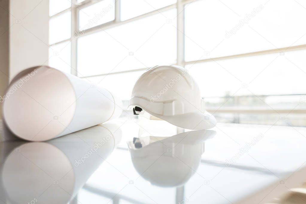 white helmet, blueprints of a building on a construction site on a window background