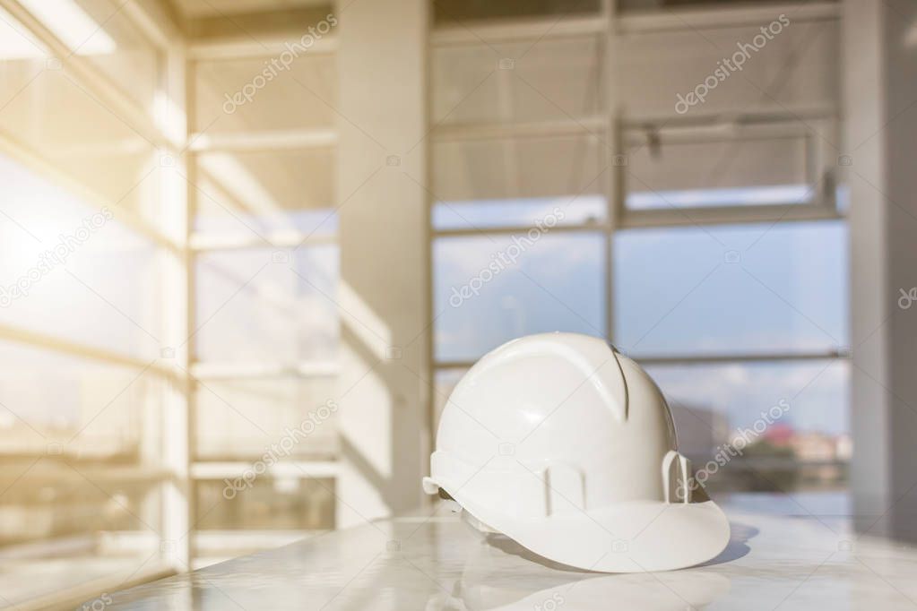white helmet, blueprints of a building on a construction site on a window background