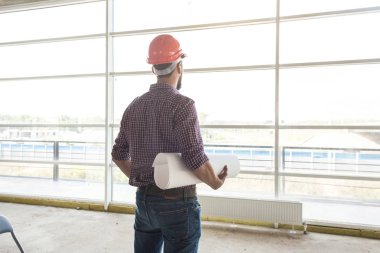 adam ile kağıt çizim, tamamlanmakta inşaat ile kareli gömlekli bir kask içinde bir mühendistir. Yapı Denetim