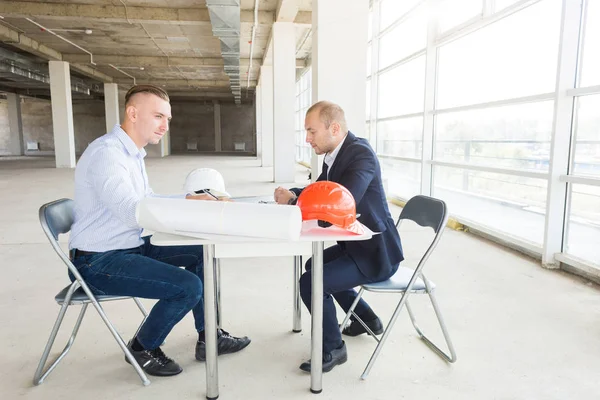 Hombres ingenieros constructores que trabajan en la mesa con un ordenador portátil, negociaciones comerciales en el sitio de construcción. ganga, compra de apartamento, bienes raíces — Foto de Stock