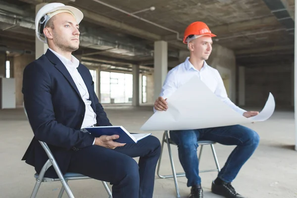 Hombres ingenieros constructores que trabajan en la mesa con un ordenador portátil, negociaciones comerciales en el sitio de construcción. ganga, compra de apartamento, bienes raíces — Foto de Stock