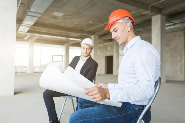 Hombres ingenieros constructores que trabajan en la mesa con un ordenador portátil, negociaciones comerciales en el sitio de construcción. ganga, compra de apartamento, bienes raíces — Foto de Stock