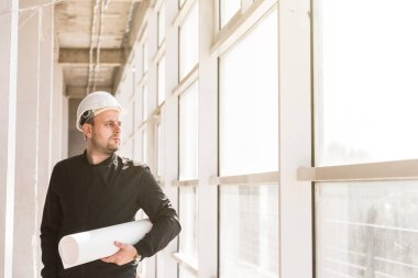 çizimleri ile bir kask içinde builder mimar inşaat alanında çalışıyor. inşaat gözetimi. pazarlık, daire satın alma, gayrimenkul