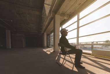 çizimleri ile bir kask içinde builder mimar inşaat alanında çalışıyor. inşaat gözetimi.