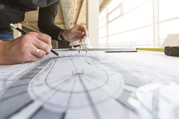 architect builder works at the table with drawings. Helmet, drawings, compasses in the workplace