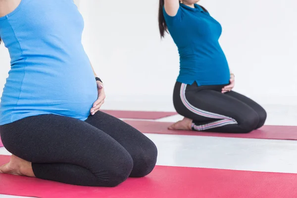 Schwangerschaft, Sport, Fitness, Menschen und gesundes Lebensstil-Konzept - Gruppe von glücklichen Schwangeren, die Yoga und Meditation in Lotus-Pose vor weißem Hintergrund ausüben — Stockfoto