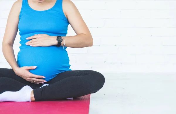 pregnancy, sport, fitness, people and healthy lifestyle concept - happy pregnant woman exercising yoga and and meditating in lotus pose in white background gym