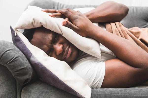 Sleepy guy waking up early after hearing alarm clock signal and does not want to get up.