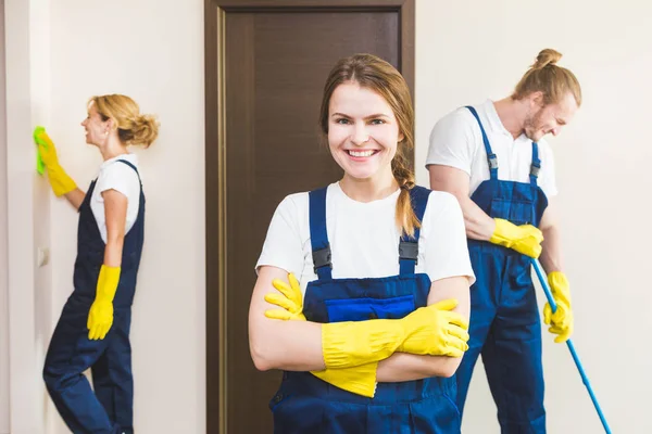 Layanan pembersihan dengan peralatan profesional selama bekerja. membersihkan dapur profesional, sofa dry cleaning, jendela dan pencucian lantai. pria dan wanita berseragam, semuanya dan sarung tangan karet — Stok Foto