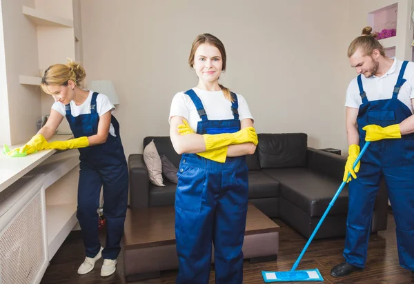 Serviço de limpeza com equipamento profissional durante o trabalho. limpeza kitchenette profissional, sofá limpeza a seco, janela e lavagem de piso. homem e mulher de uniforme, macacão e luvas de borracha — Fotografia de Stock