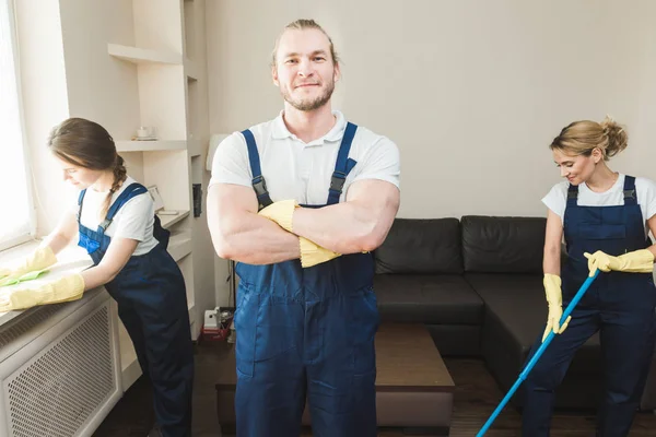 Serviço de limpeza com equipamento profissional durante o trabalho. limpeza kitchenette profissional, sofá limpeza a seco, janela e lavagem de piso. homem e mulher de uniforme, macacão e luvas de borracha — Fotografia de Stock