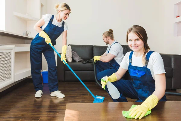 Serviço de limpeza com equipamento profissional durante o trabalho. limpeza kitchenette profissional, sofá limpeza a seco, janela e lavagem de piso. homem e mulher de uniforme, macacão e luvas de borracha — Fotografia de Stock