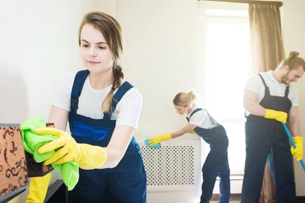 Layanan pembersihan dengan peralatan profesional selama bekerja. membersihkan dapur profesional, sofa dry cleaning, jendela dan pencucian lantai. pria dan wanita berseragam, semuanya dan sarung tangan karet — Stok Foto