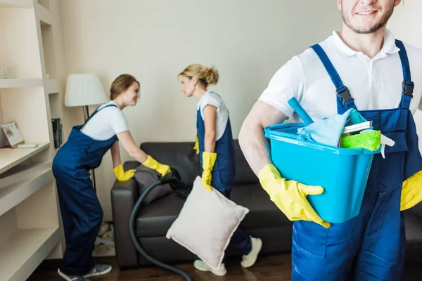 Cleaning service with professional equipment during work. professional kitchenette cleaning, sofa dry cleaning, window and floor washing. man and women in uniform, overalls and rubber gloves