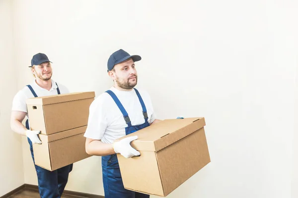 Uomo di consegna che carica scatole di cartone per trasferirsi in un appartamento. lavoratore professionista del trasporto, caricatori maschili in tuta intera — Foto Stock