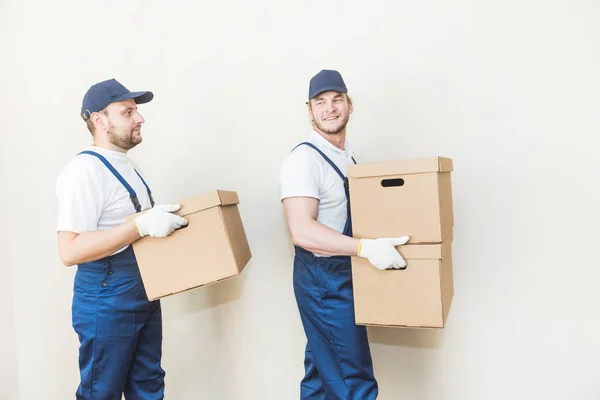 Uomo di consegna che carica scatole di cartone per trasferirsi in un appartamento. lavoratore professionista del trasporto, caricatori maschili in tuta intera — Foto Stock