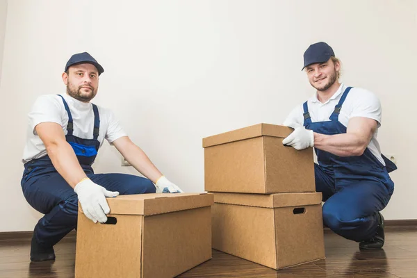Uomo di consegna che carica scatole di cartone per trasferirsi in un appartamento. lavoratore professionista del trasporto, caricatori maschili in tuta intera — Foto Stock