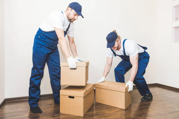 Uomo di consegna che carica scatole di cartone per trasferirsi in un appartamento. lavoratore professionista del trasporto, caricatori maschili in tuta intera — Foto Stock