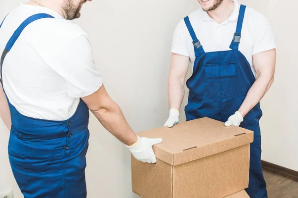 Uomo di consegna che carica scatole di cartone per trasferirsi in un appartamento. lavoratore professionista del trasporto, caricatori maschili in tuta intera — Foto Stock