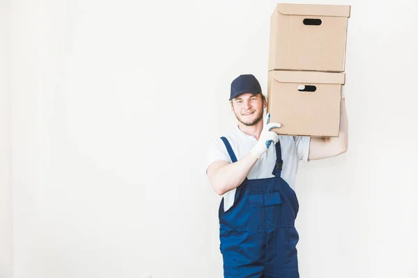 Consegna forte, uomo muscoloso caricare scatole di cartone per il trasferimento in un appartamento. lavoratore professionista dei trasporti, caricatori maschili in tuta. spazio libero per testo, isolato — Foto Stock