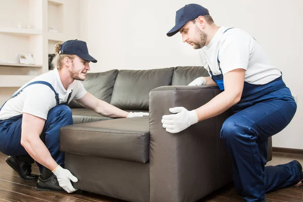 Consegna uomo spostare mobili trasportare divano per trasferirsi in un appartamento. lavoratore professionista del trasporto, caricatori maschili in tuta intera — Foto Stock