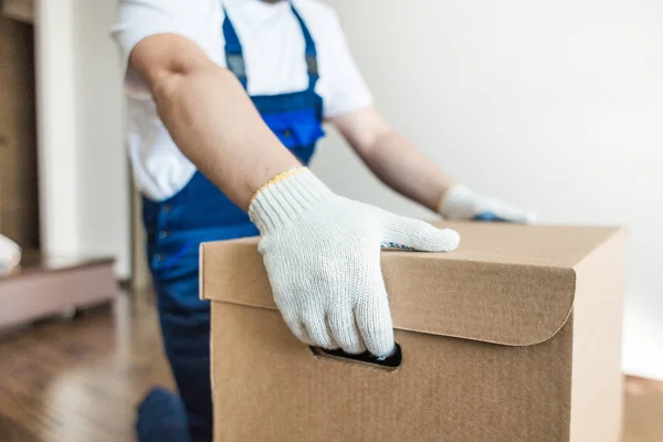 Uomo di consegna che carica scatole di cartone per trasferirsi in un appartamento. lavoratore professionista del trasporto, caricatori maschili in tuta intera — Foto Stock