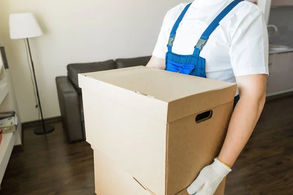 Uomo di consegna che carica scatole di cartone per trasferirsi in un appartamento. lavoratore professionista del trasporto, caricatori maschili in tuta intera — Foto Stock