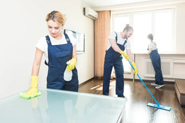 Υπηρεσία καθαρισμού με επαγγελματικό εξοπλισμό κατά τη διάρκεια της εργασίας. επαγγελματικό καθάρισμα κουζινών, καναπές στεγνό καθάρισμα, παράθυρο και πλύσιμο δαπέδων. Άνδρες και γυναίκες με στολή, φόρμα και λαστιχένια γάντια — Φωτογραφία Αρχείου